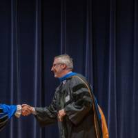 President Mantella shakes hands with man on stage